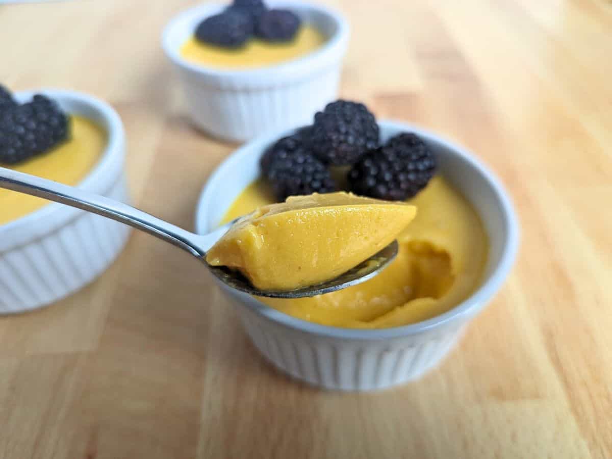 Small bowl filled with mango mousse and topped with blackberries.