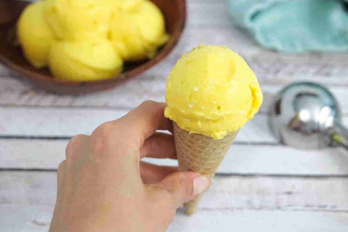 Scoop of mango ice cream on a waffle cone.