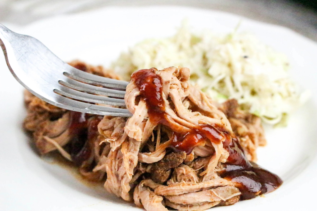 A forkful of shredded pork topped topped with bbq sauce.