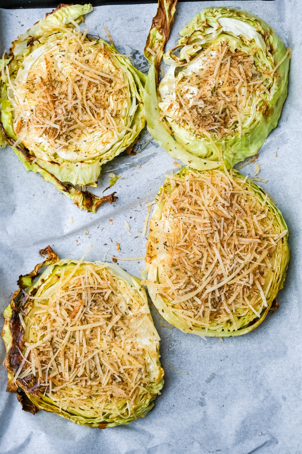 Sliced cabbage steaks topped with parmesan cheese before finishing roasting.