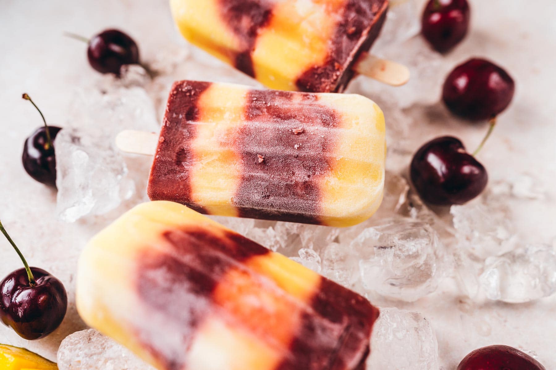 Mango and cherry popiscles on top of ice.
