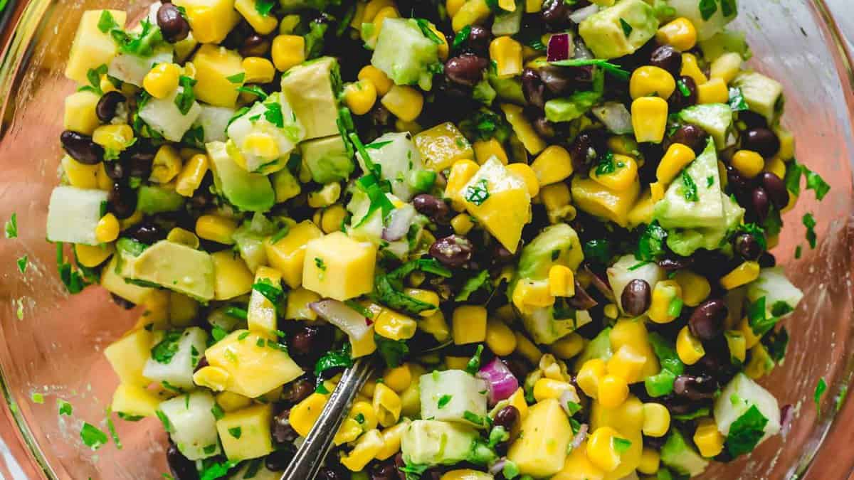 Glass bowl full of mango black bean salad on a table.