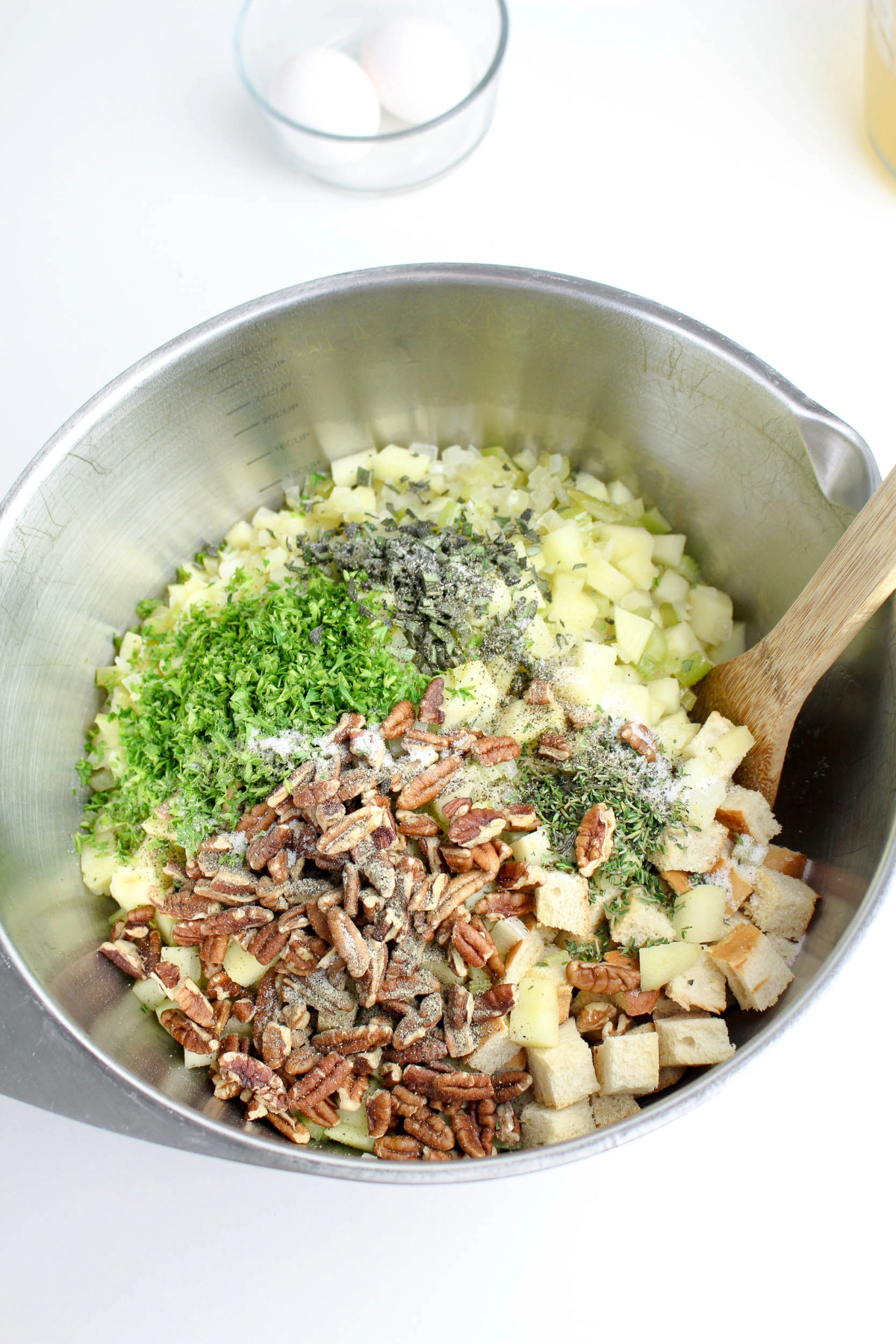 Pecans with cubed bread and herbs in a silver mixing bowl.