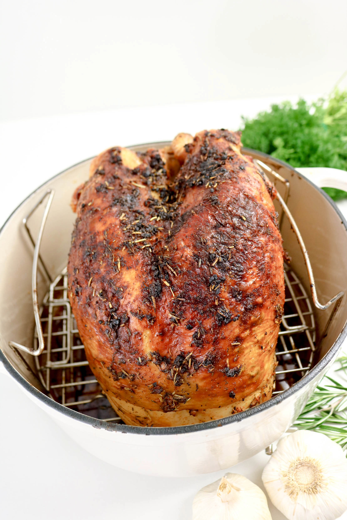 Roasted cooked turkey breasts in a white Dutch oven on a wire rack.