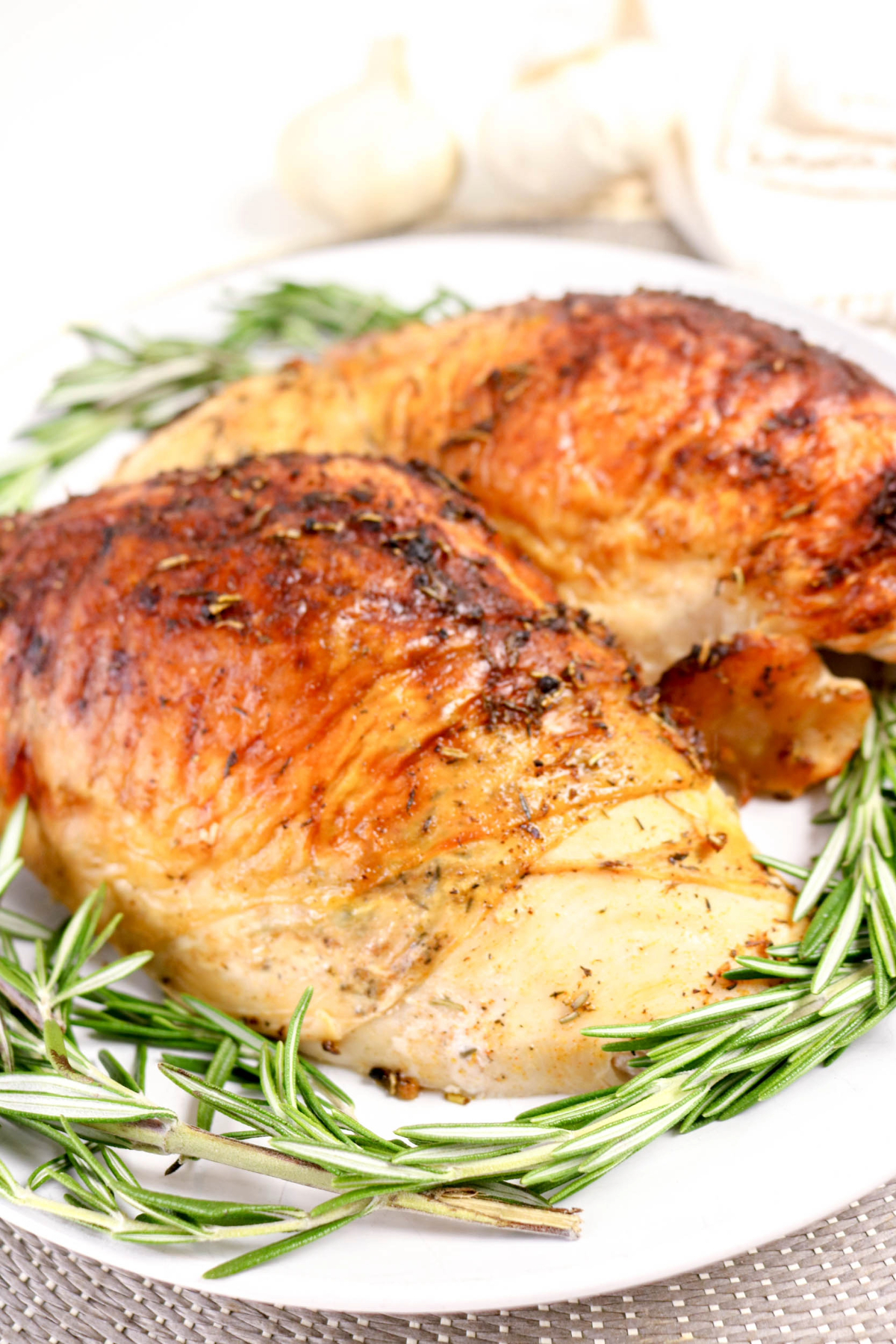 Roasted turkey breasts on a white serving platter before slicing.