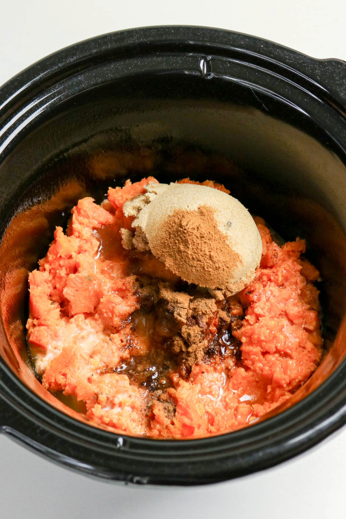 Ingredients added to sweet potatoes before mixing in a slow cooker.