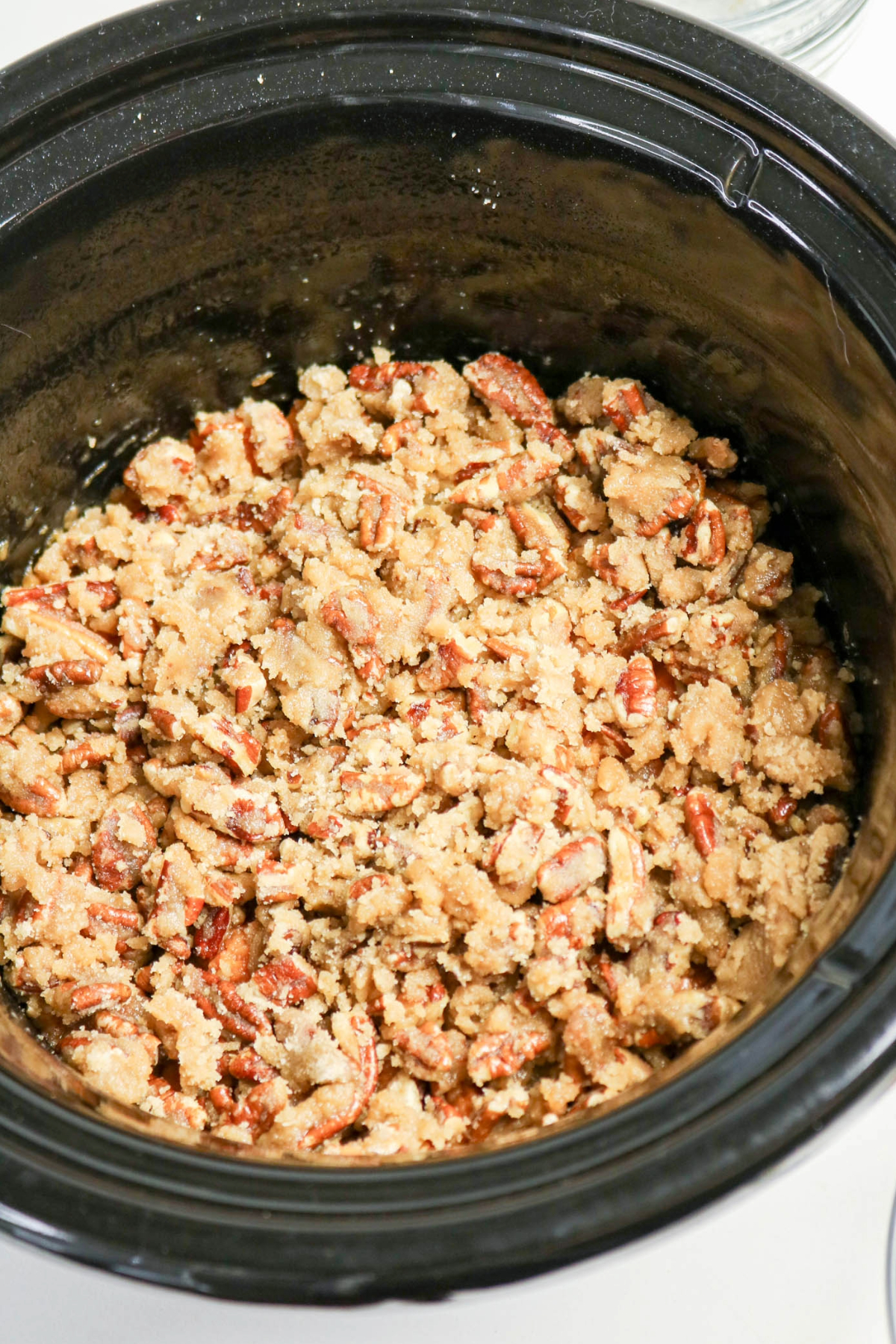 All the ingredients in a black slow cooker insert before cooking sweet potato casserole.