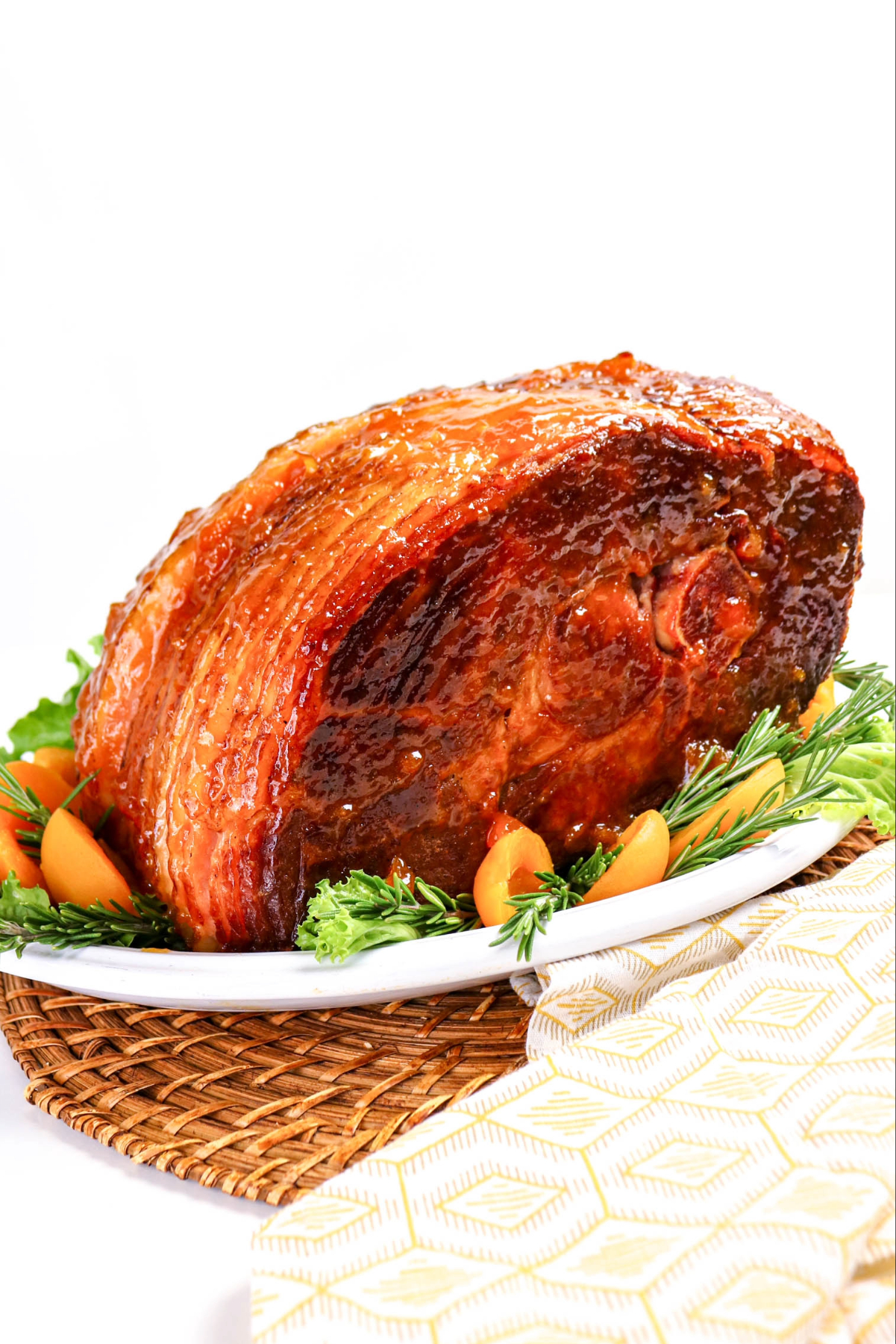 Holiday ham topped with apricot sauce on a white serving platter.