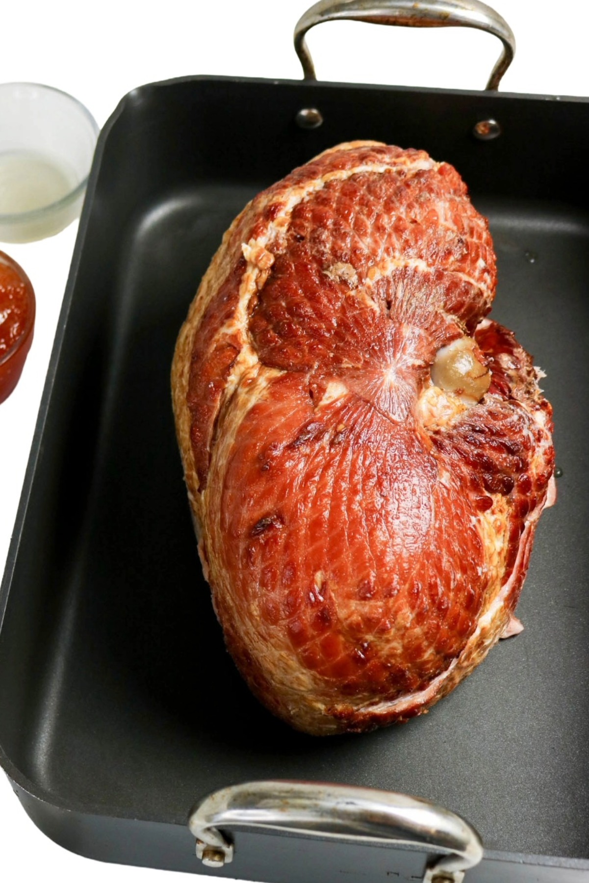 Roasting ham in a black roasting pan.