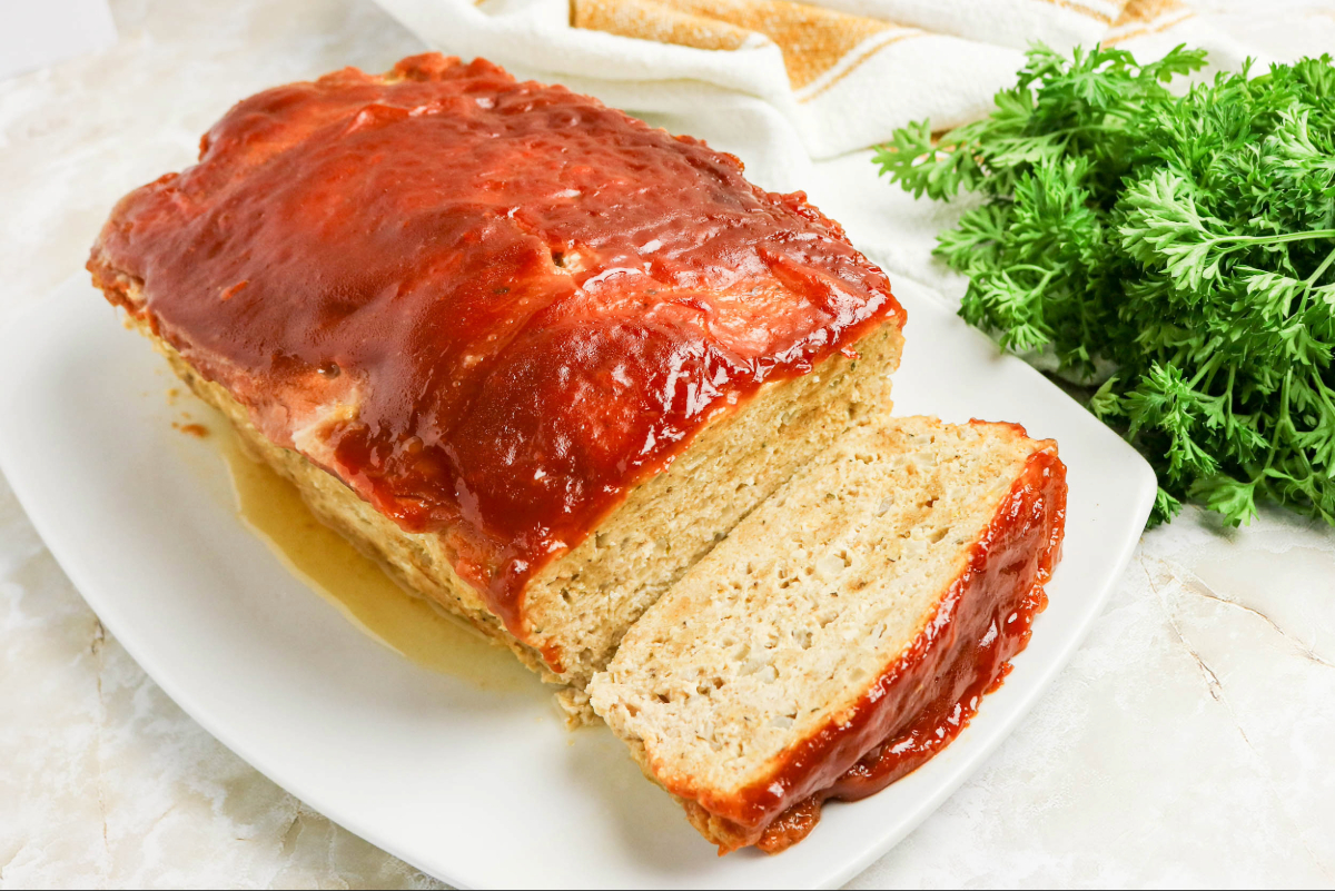 Meatloaf on a serving platter with parsley on the side.