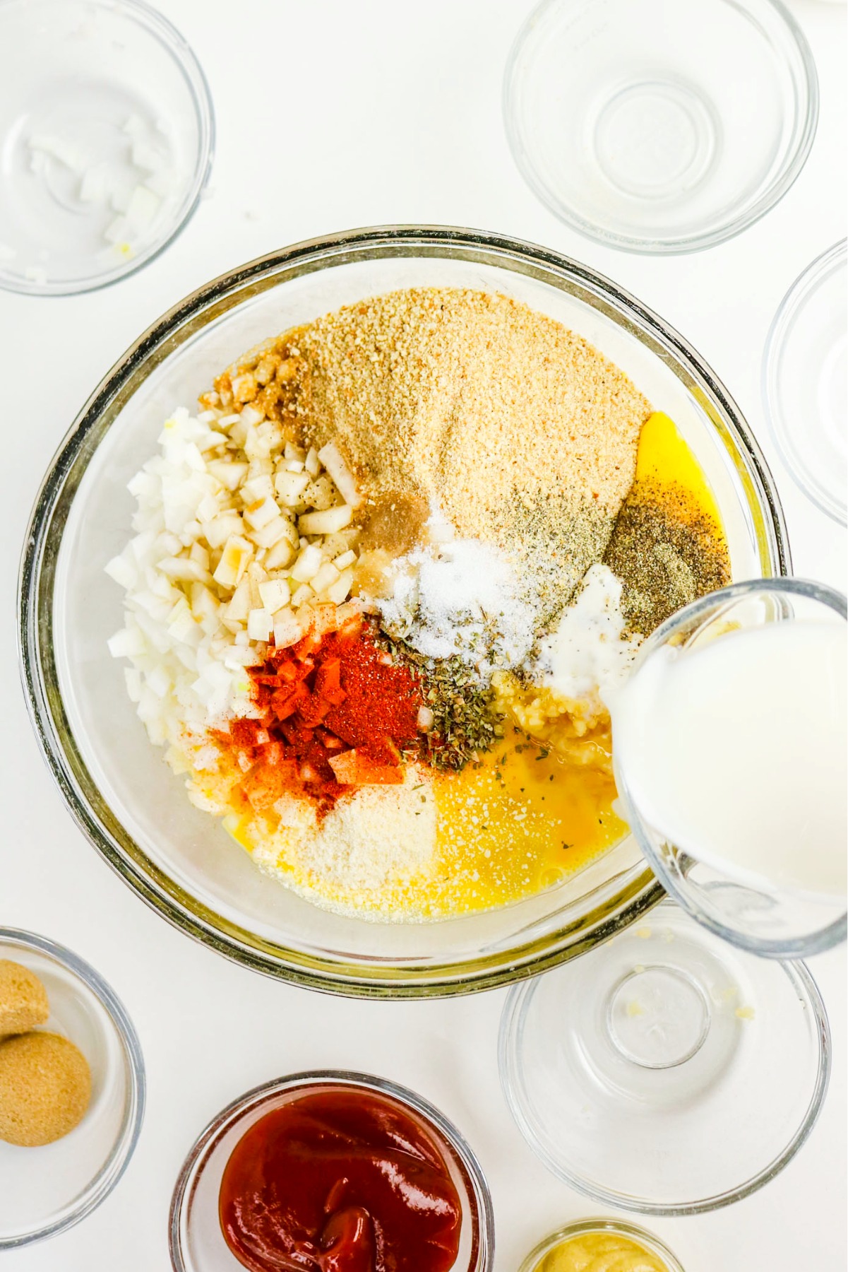 Ingredients to make meatloaf in a large clear mixing bowl.