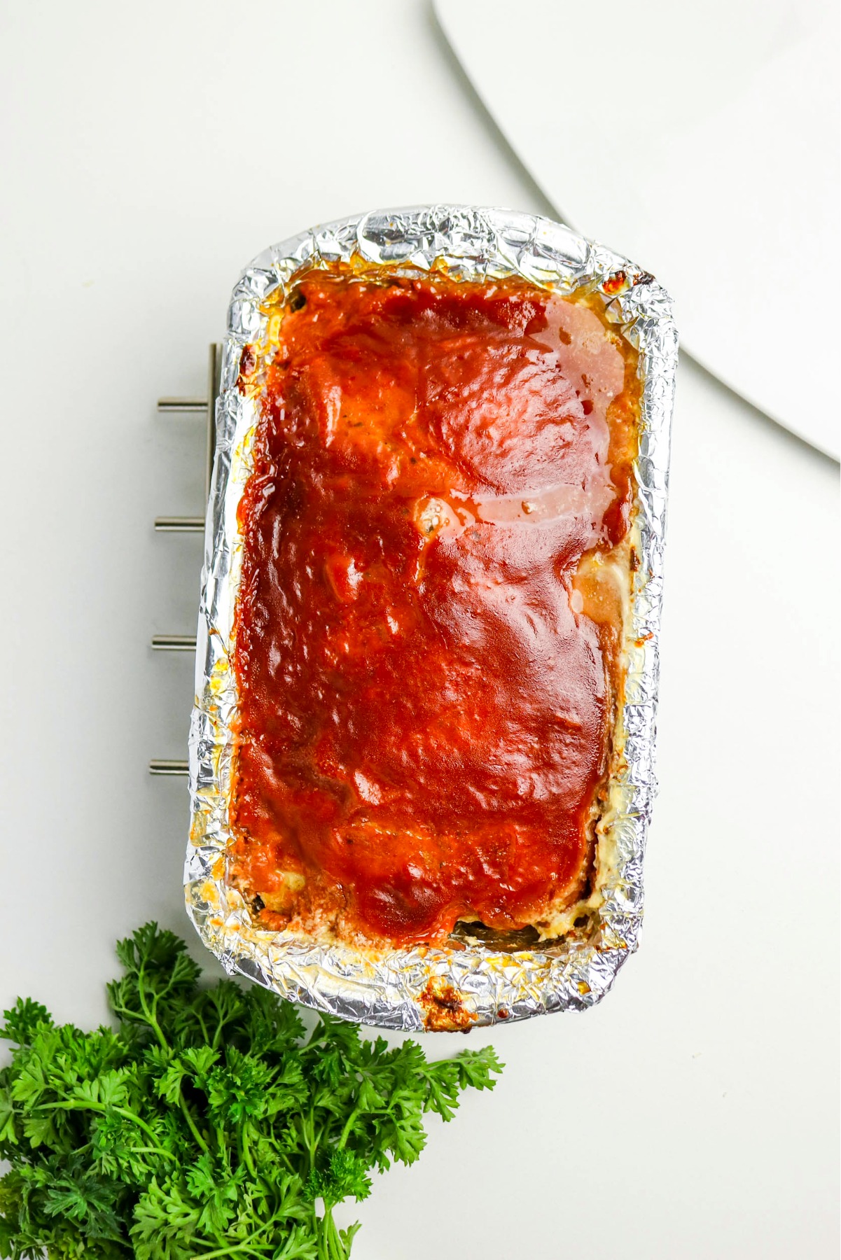 Chicken meatloaf in a loaf pan with glaze on top before baking.