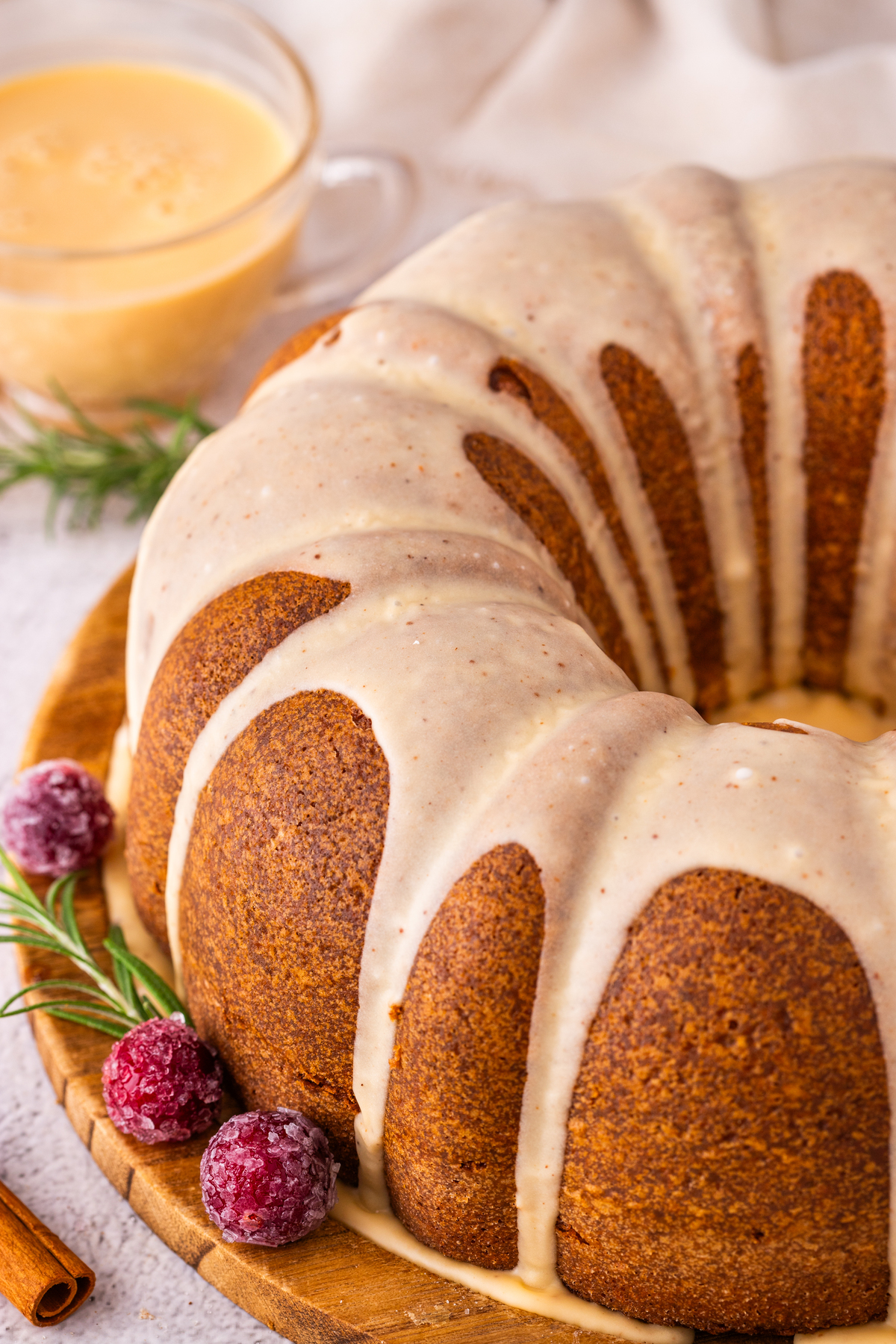 Baked bundt cake with glaze on a wooden cake stand. 