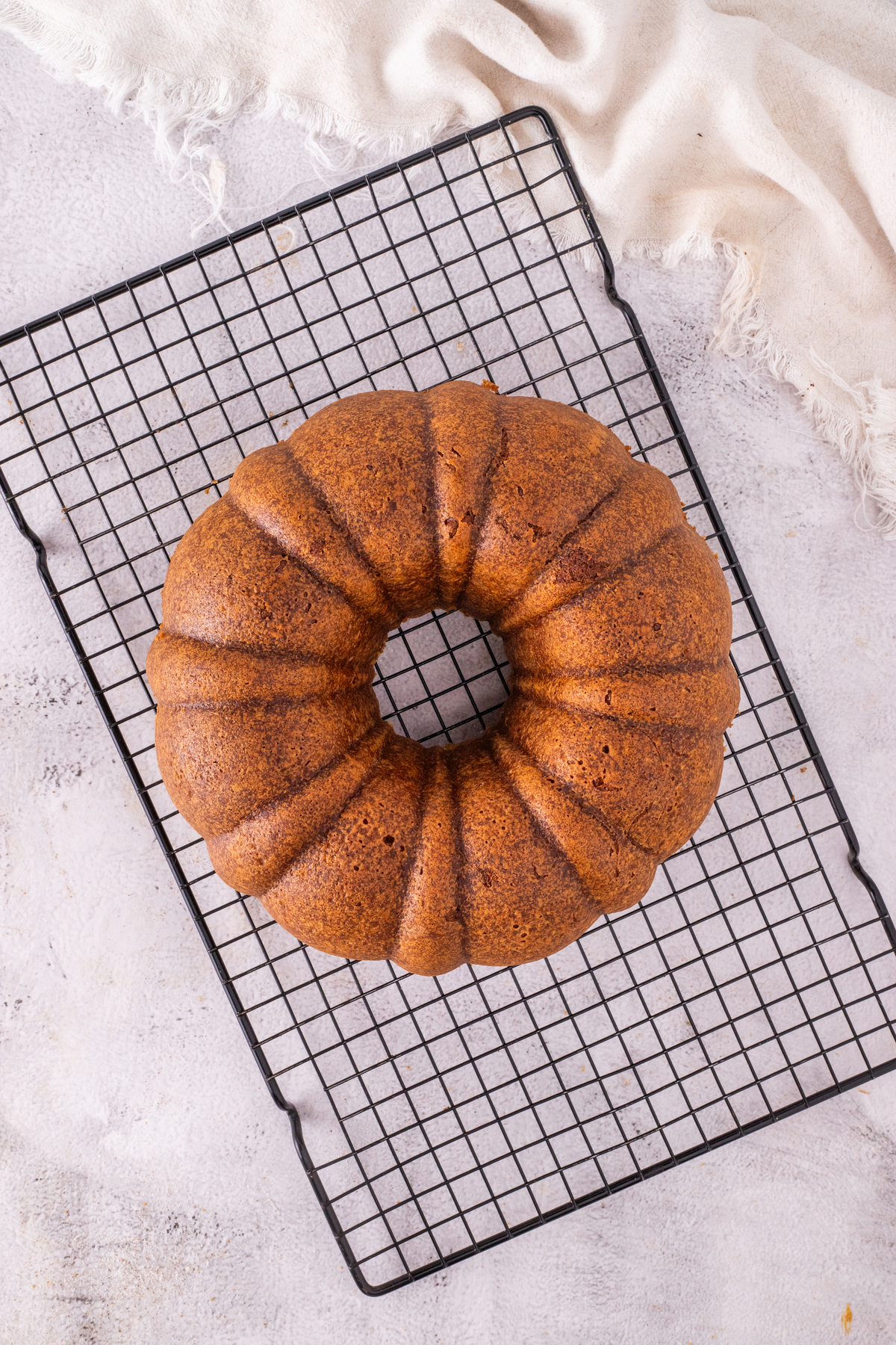 Baked bundt cake cooking on a cooling rack. 