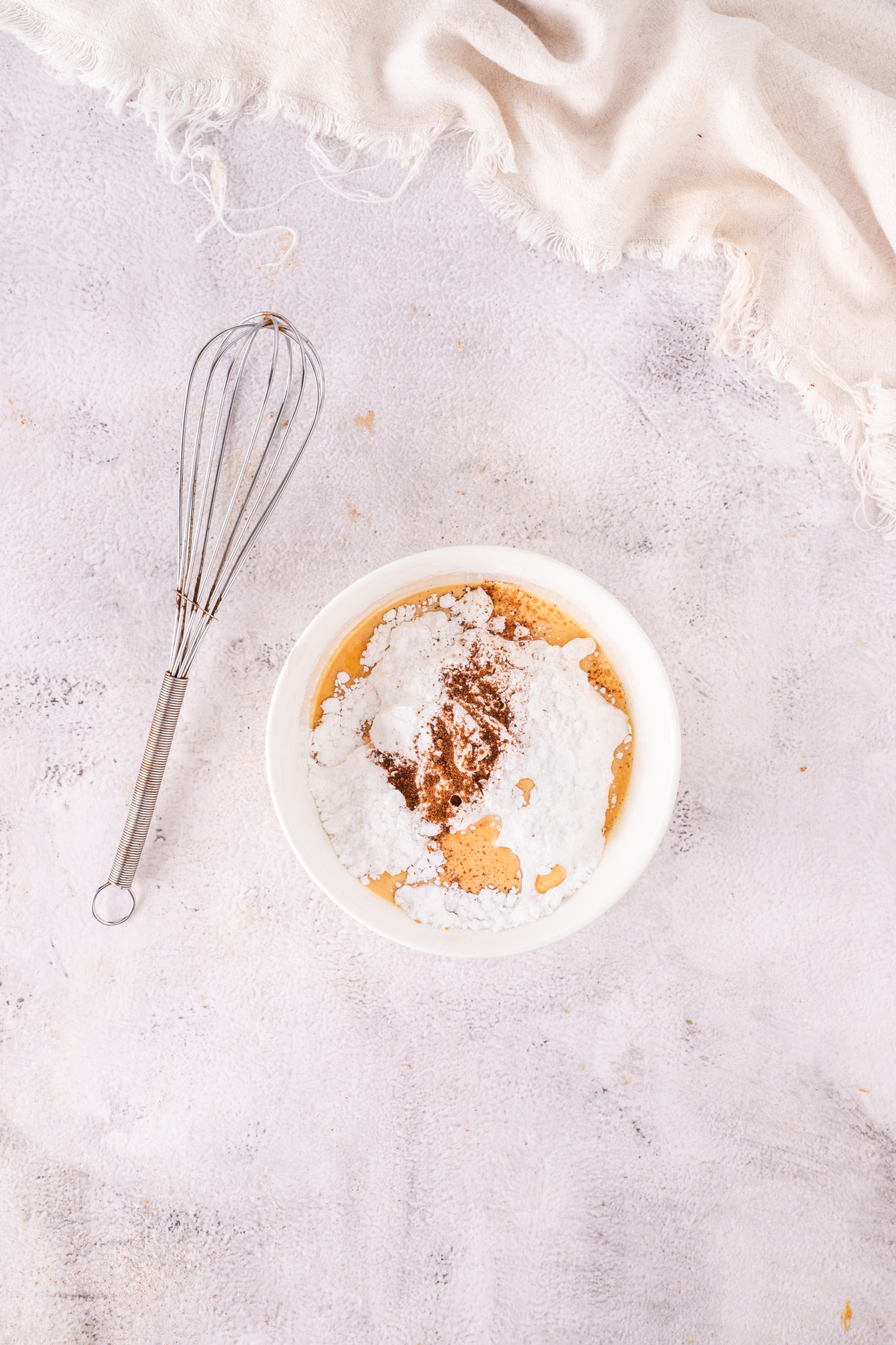 Ingredients for eggnog glaze in a small white mixing bowl.