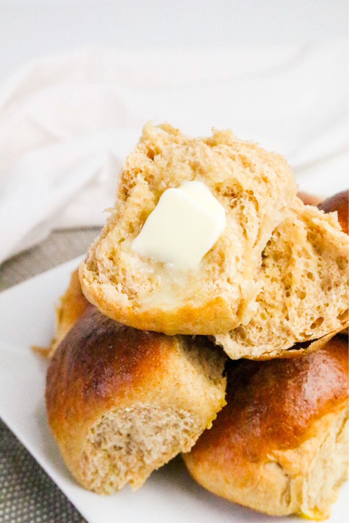 A split dinner roll with a tab of butter melting on the bread.