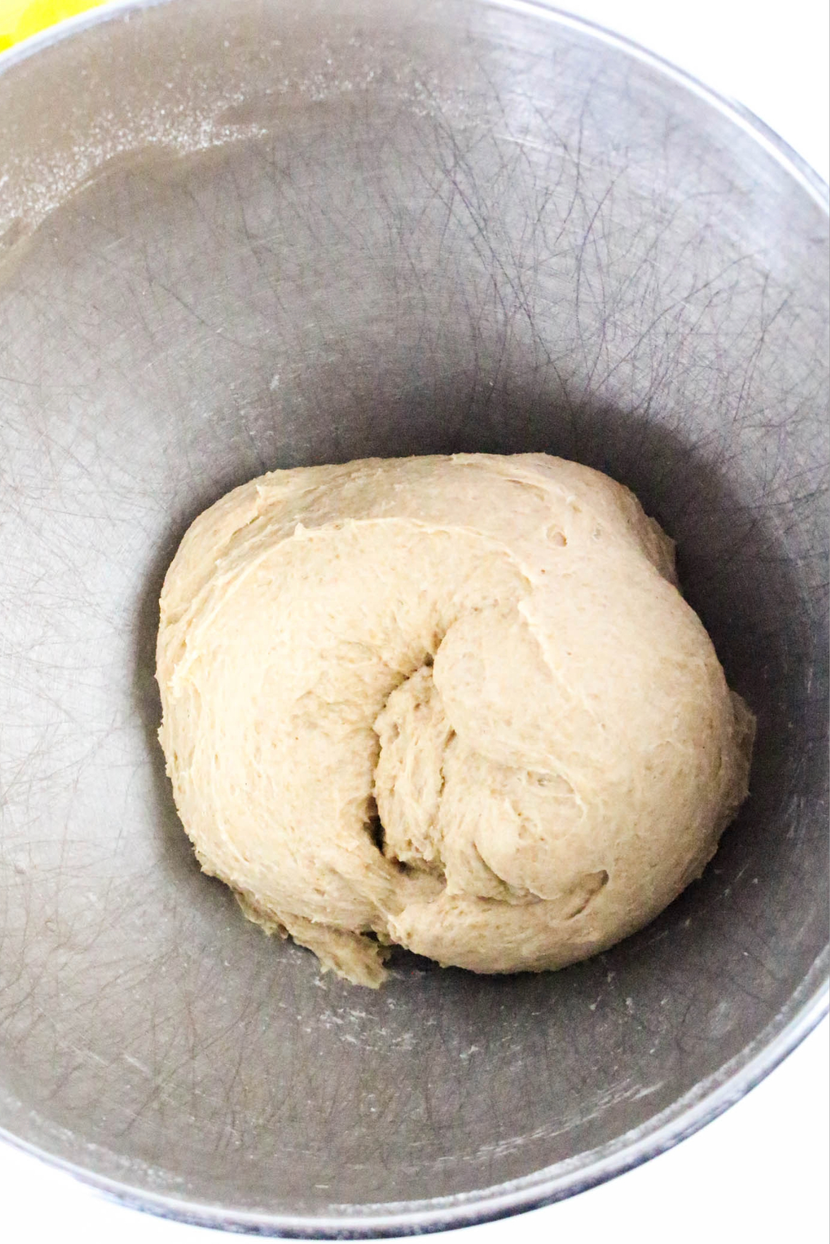 dough for dinner rolls in a silver mixing bowl.