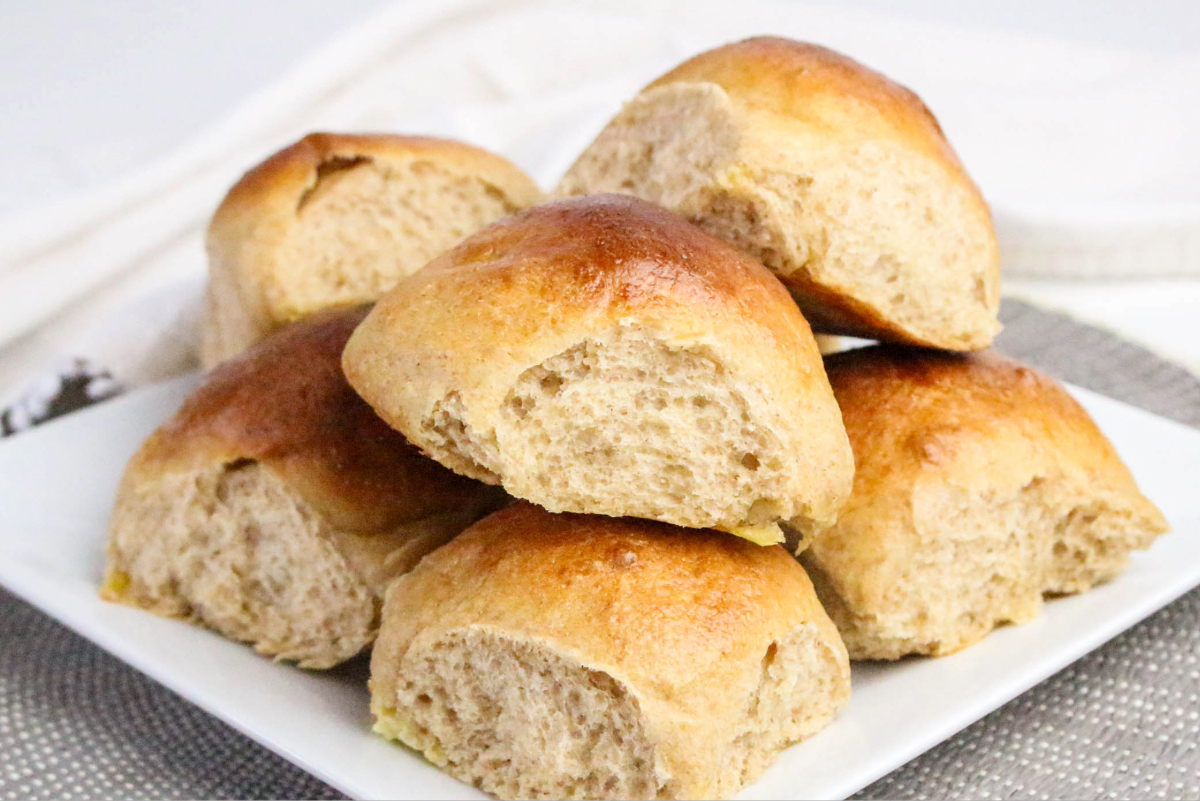 Dinner rolls on a white serving plate.