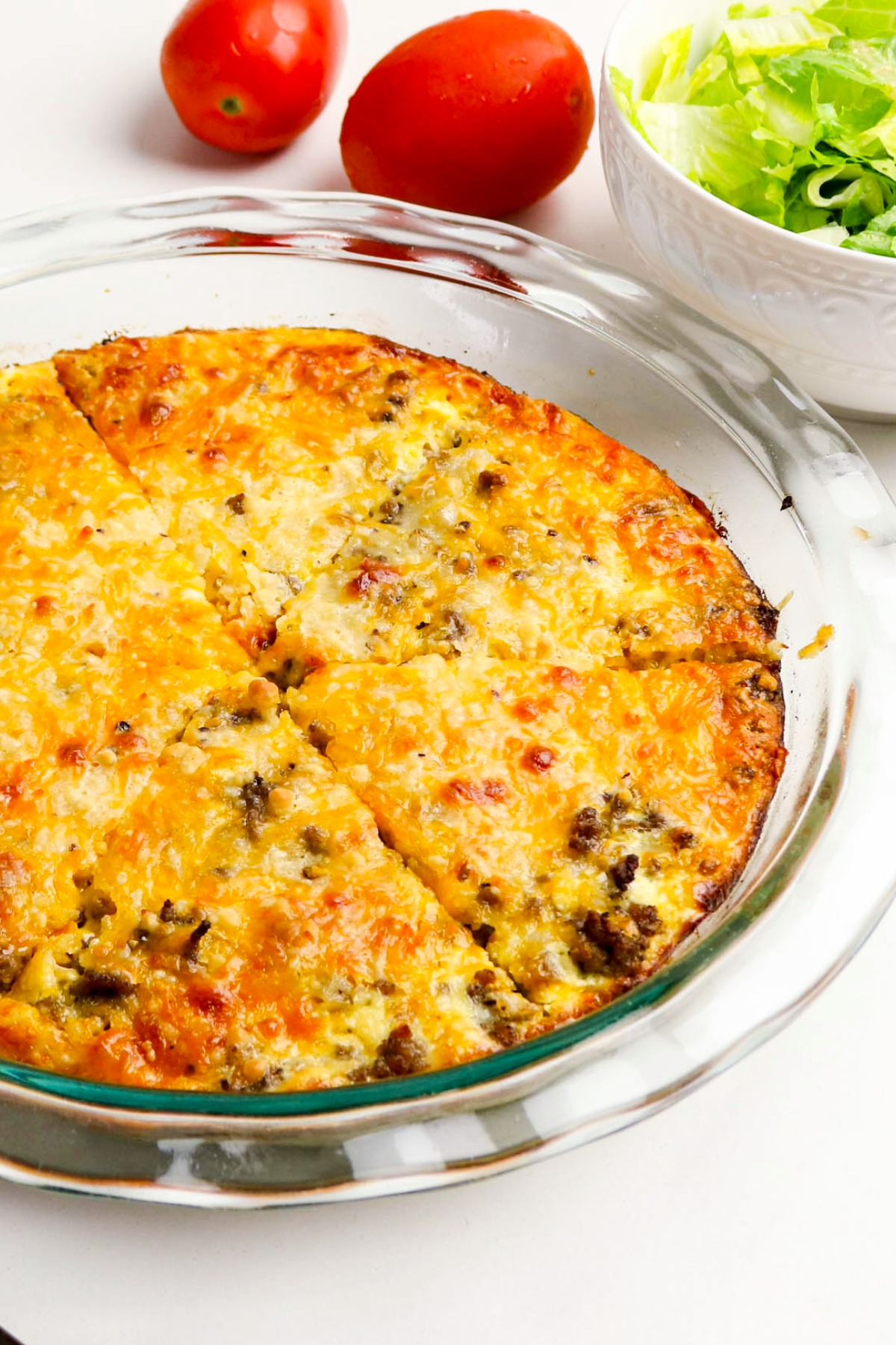 Top view of cooked sliced hamburger pie in a clear pie pan.