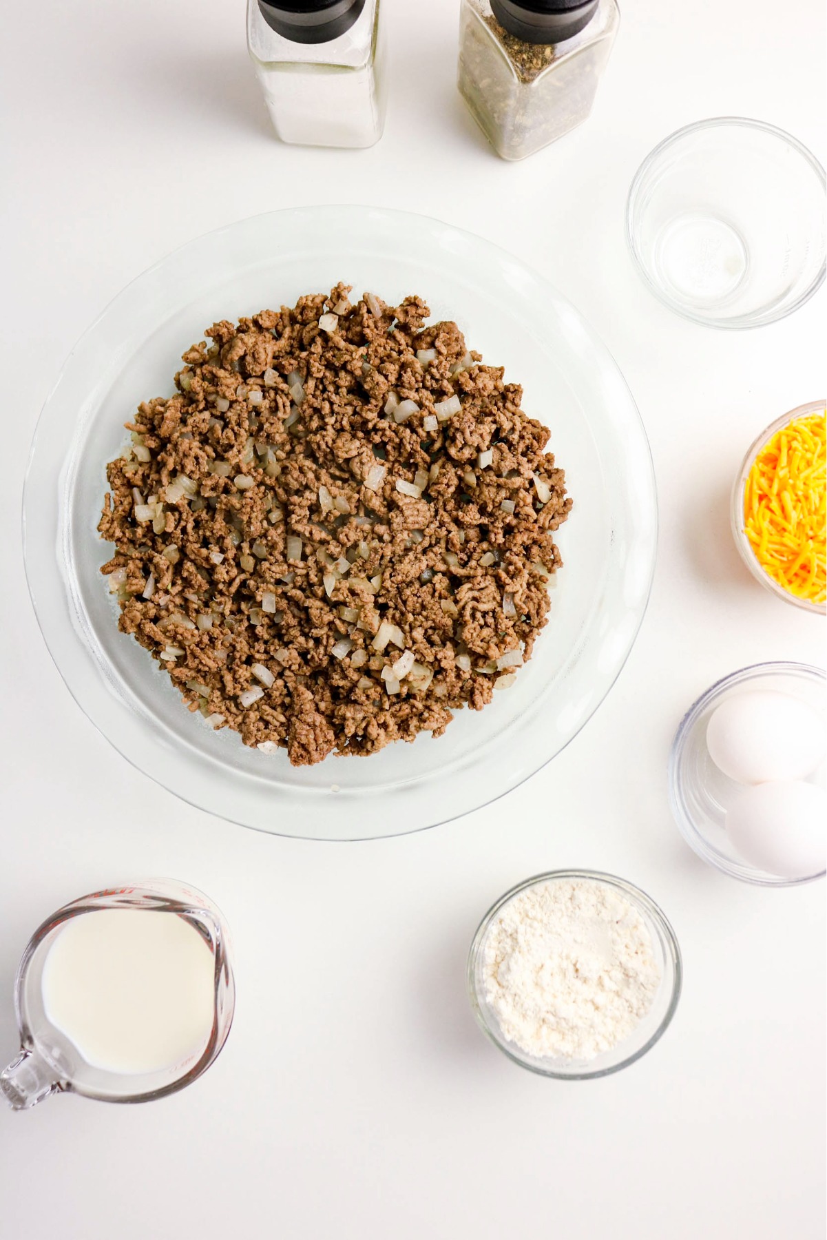 Cooked ground beef on the bottom of a pie plate.