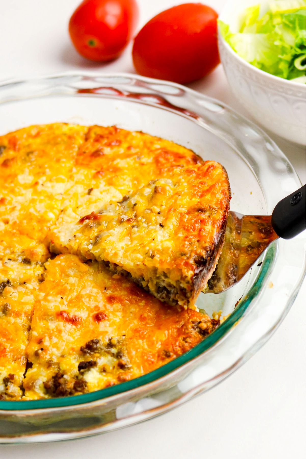 A spatula removing prepared hamburger pie from the baking dish.