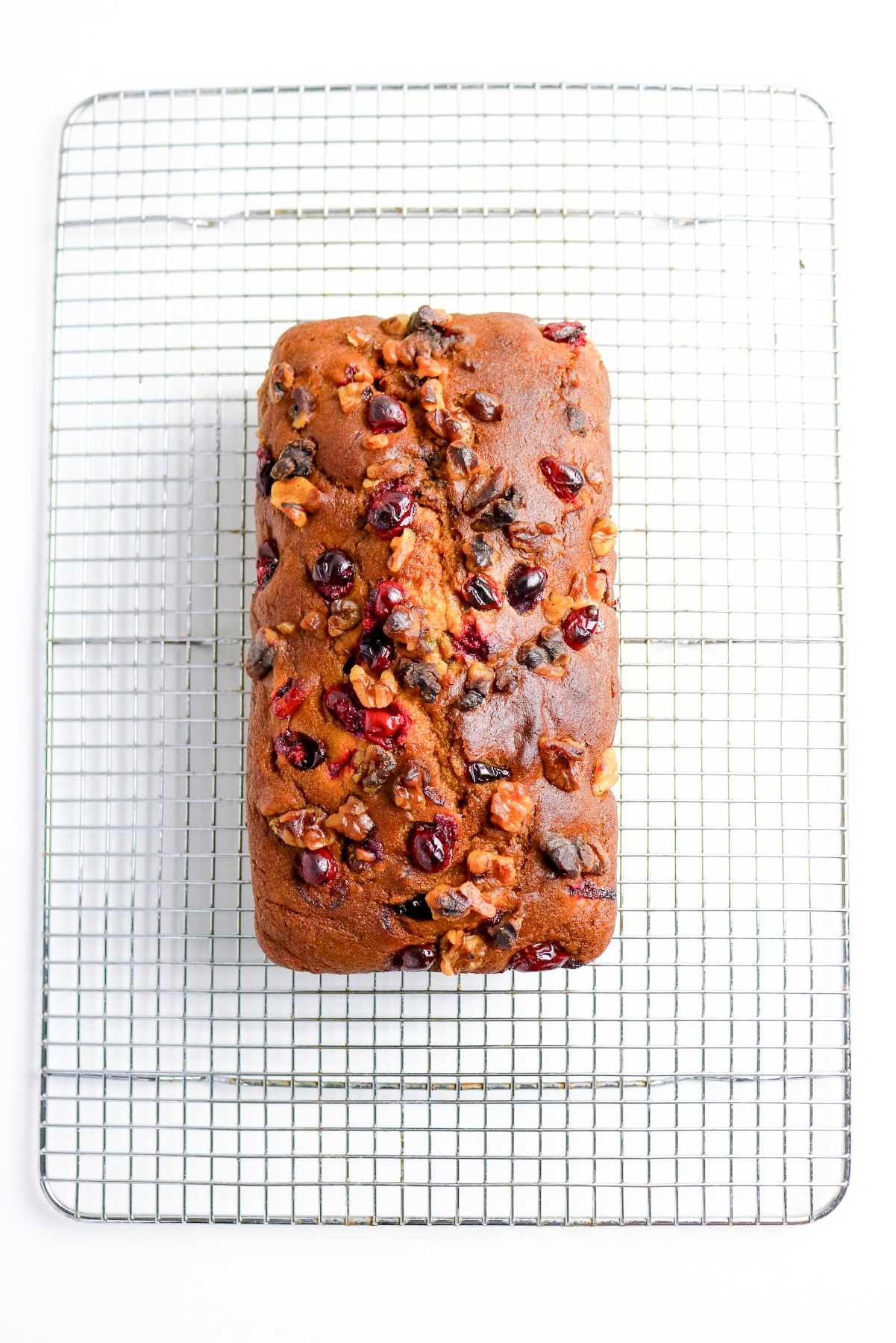 Baked pumpkin cranberry bread cooling on a wire baking rack.