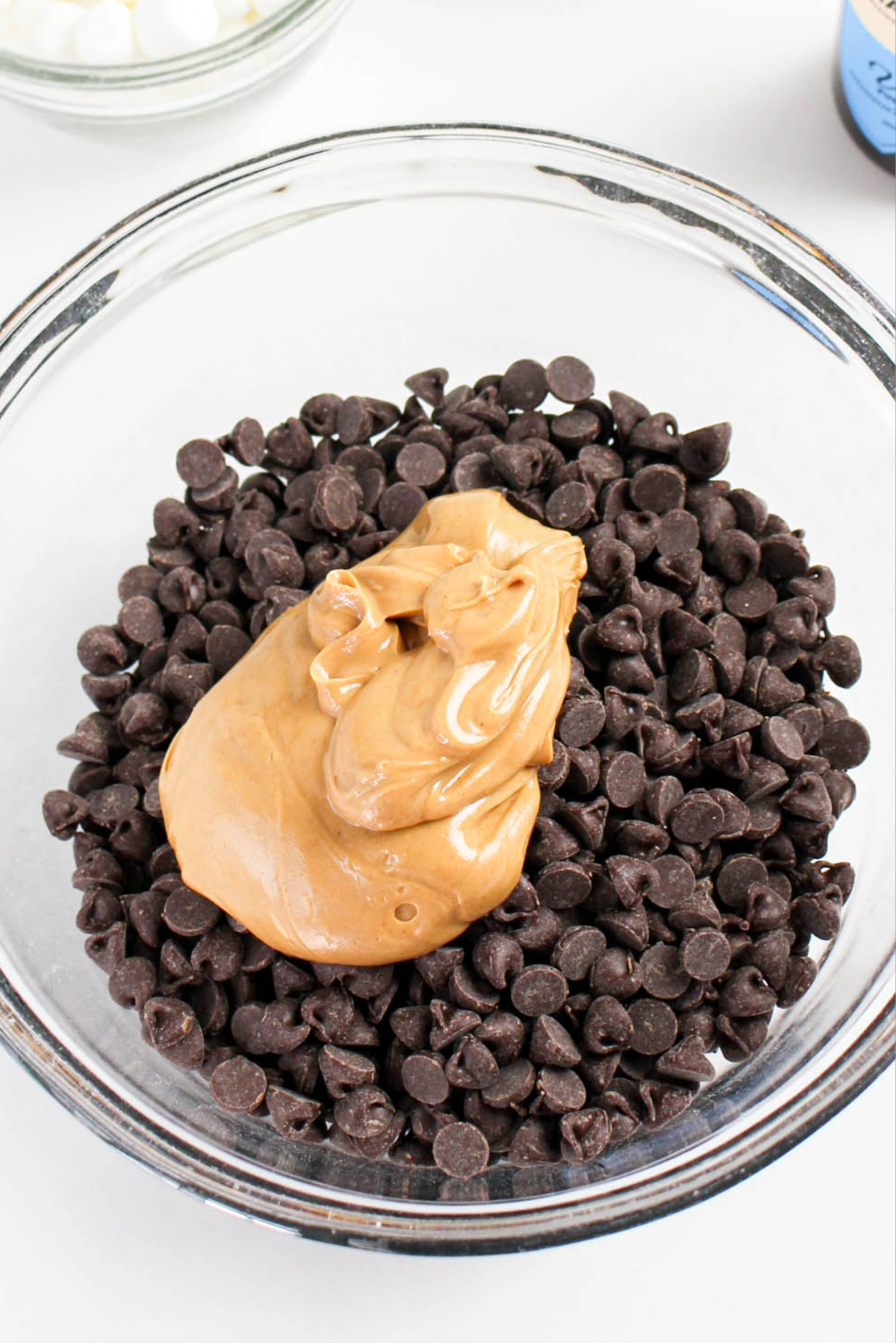 Chocolate chips and peanut butter in a clear mixing bowl before melting.