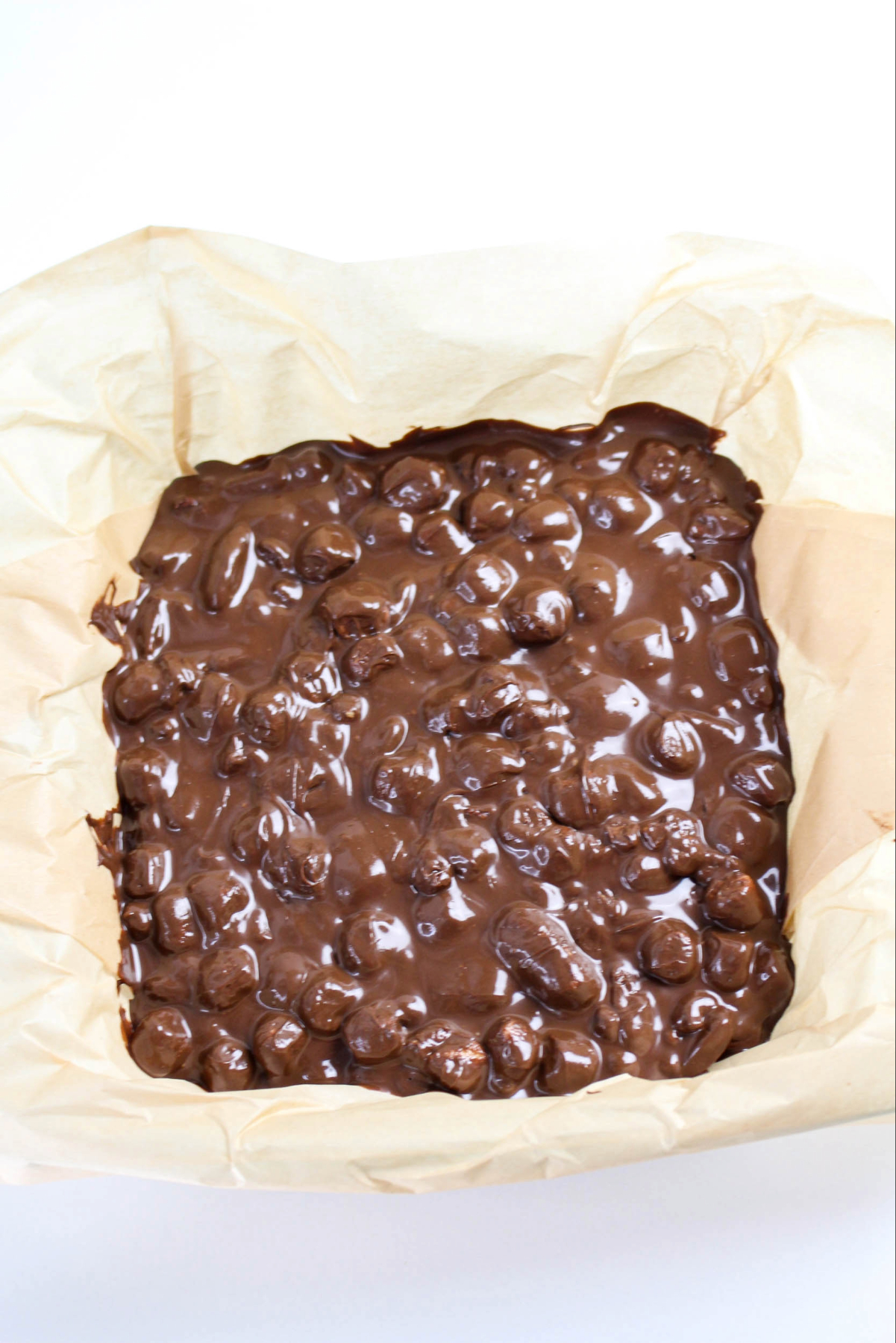Rocky road mixture in a parchment lined baking dish ready to refrigerate.