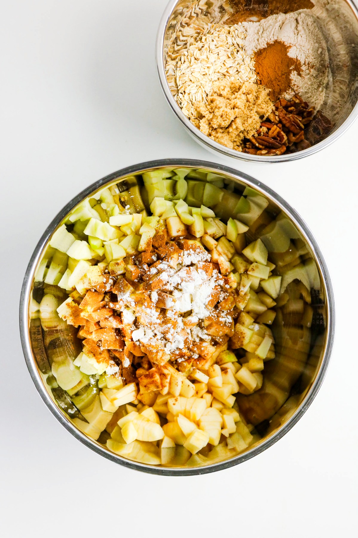 Diced apples with spices in a stainless steel mixing bowl.