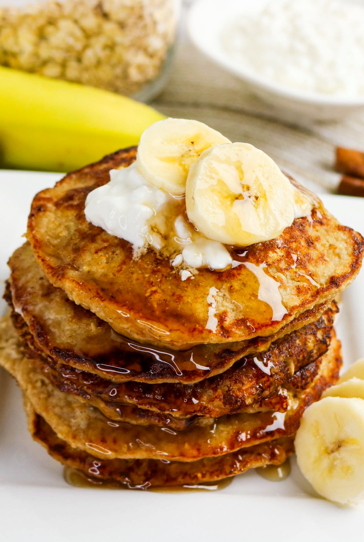 A stack of pancakes made with banana and cottage cheese on a white serving plate.