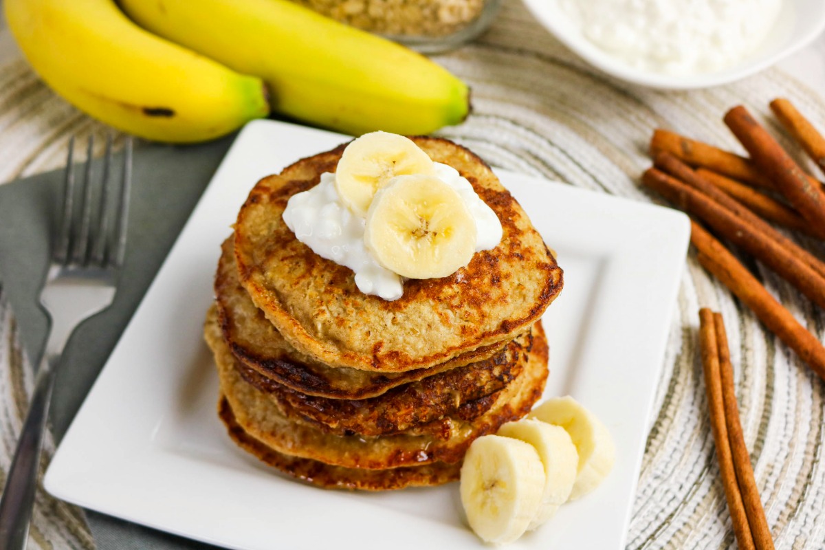 Pancakes on a plate with cinnamon sticks on the side.