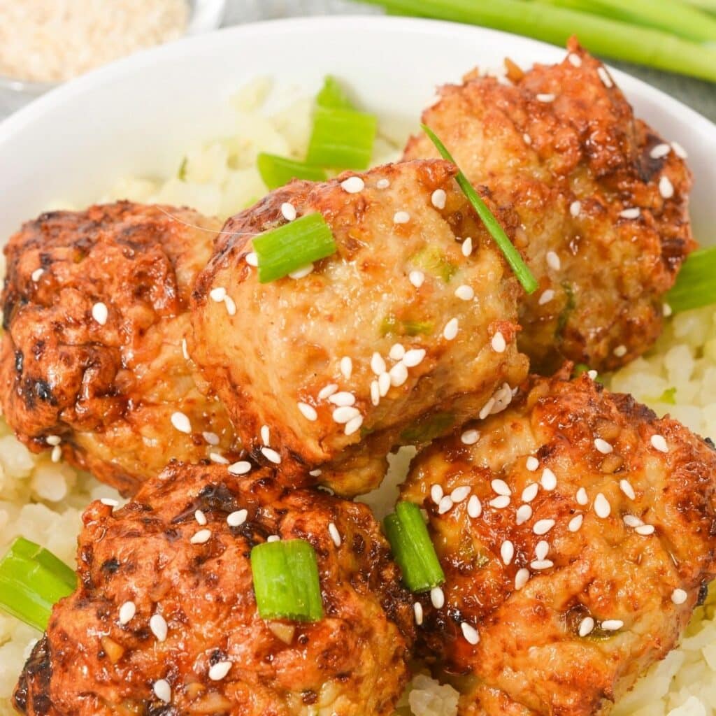 Healthy chicken meatballs that has been cooked in an air fryer topped with green onions.