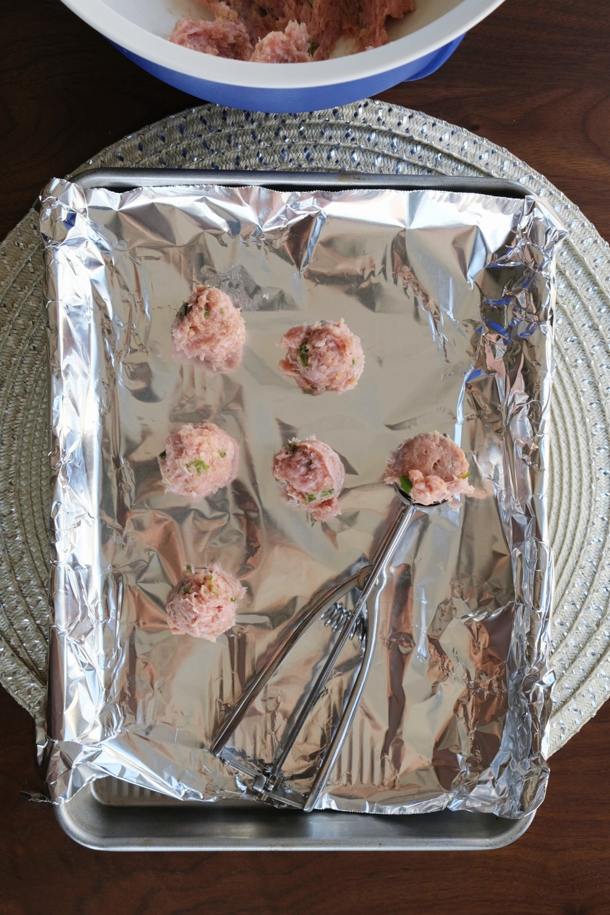 Meatballs on a baking sheet before placing in an air fyer to cook.