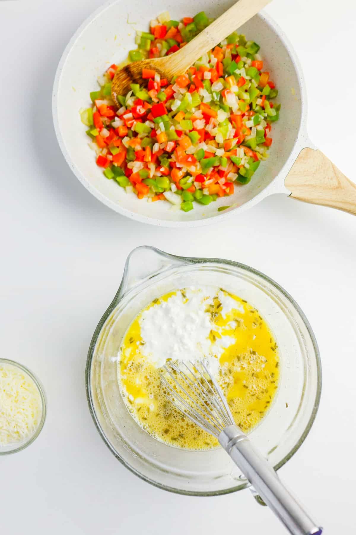 Egg mix with cottage cheese in a clear mixing bowl. Sauted bell peppers on the side.