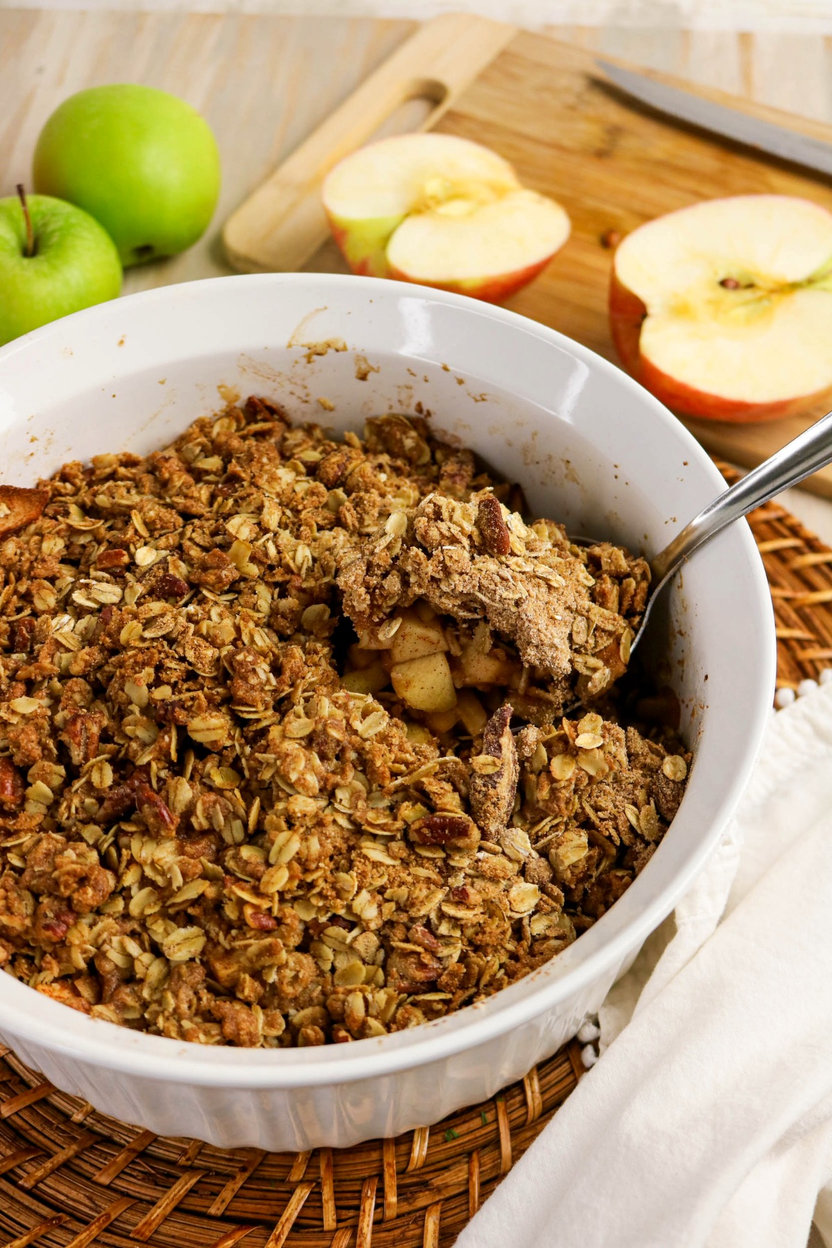 A white baking dish with baked apples topped with a low sugar crumble.