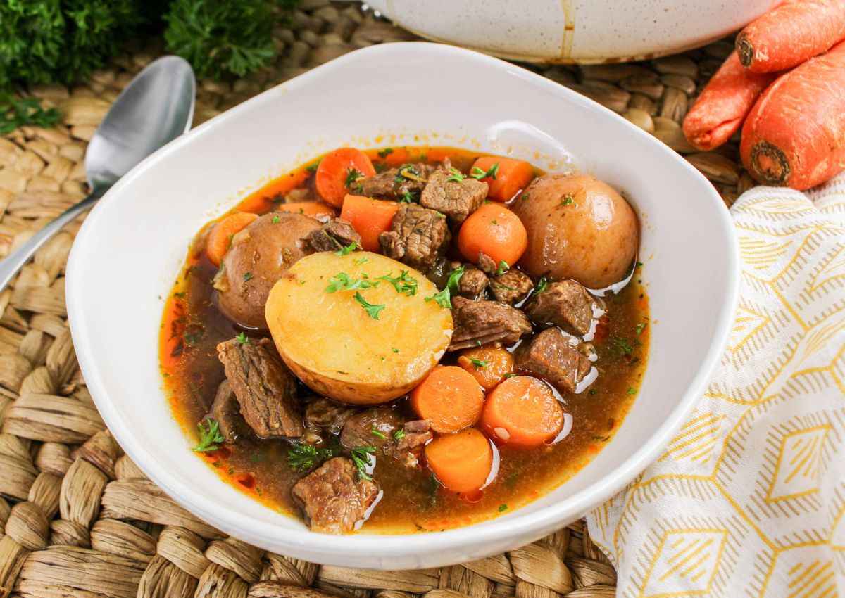 Hearty beef brisket stew served in white bowl on woven placemat.