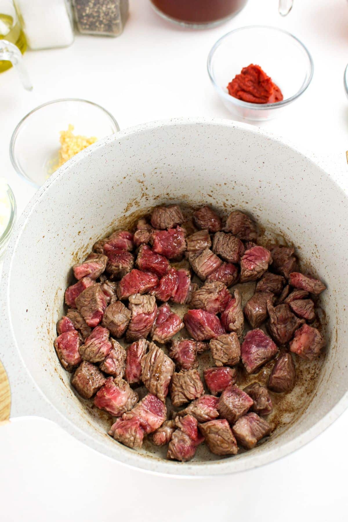 Cubed beef brisket browning in a Dutch oven before simmering.