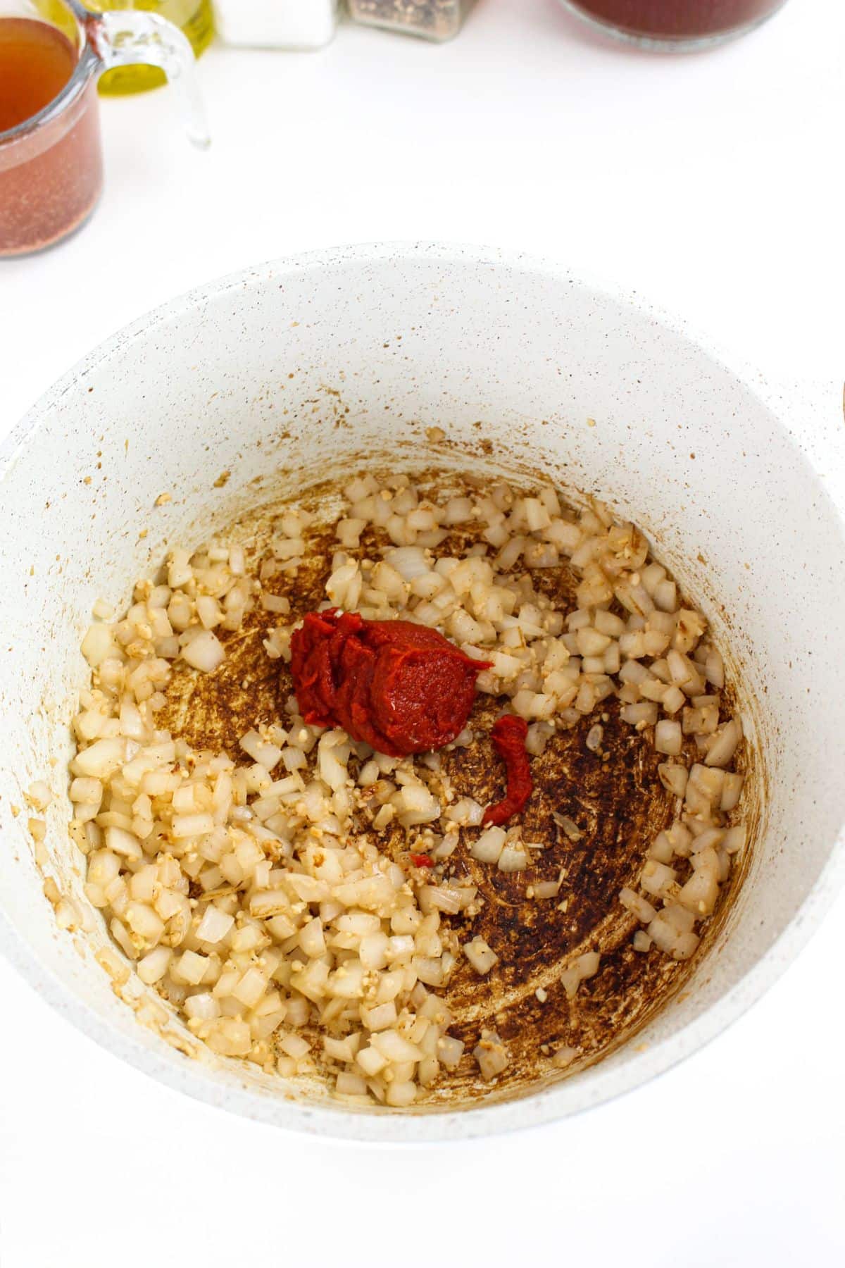 Onions and tomato paste simmering in broth inside a Dutch oven.