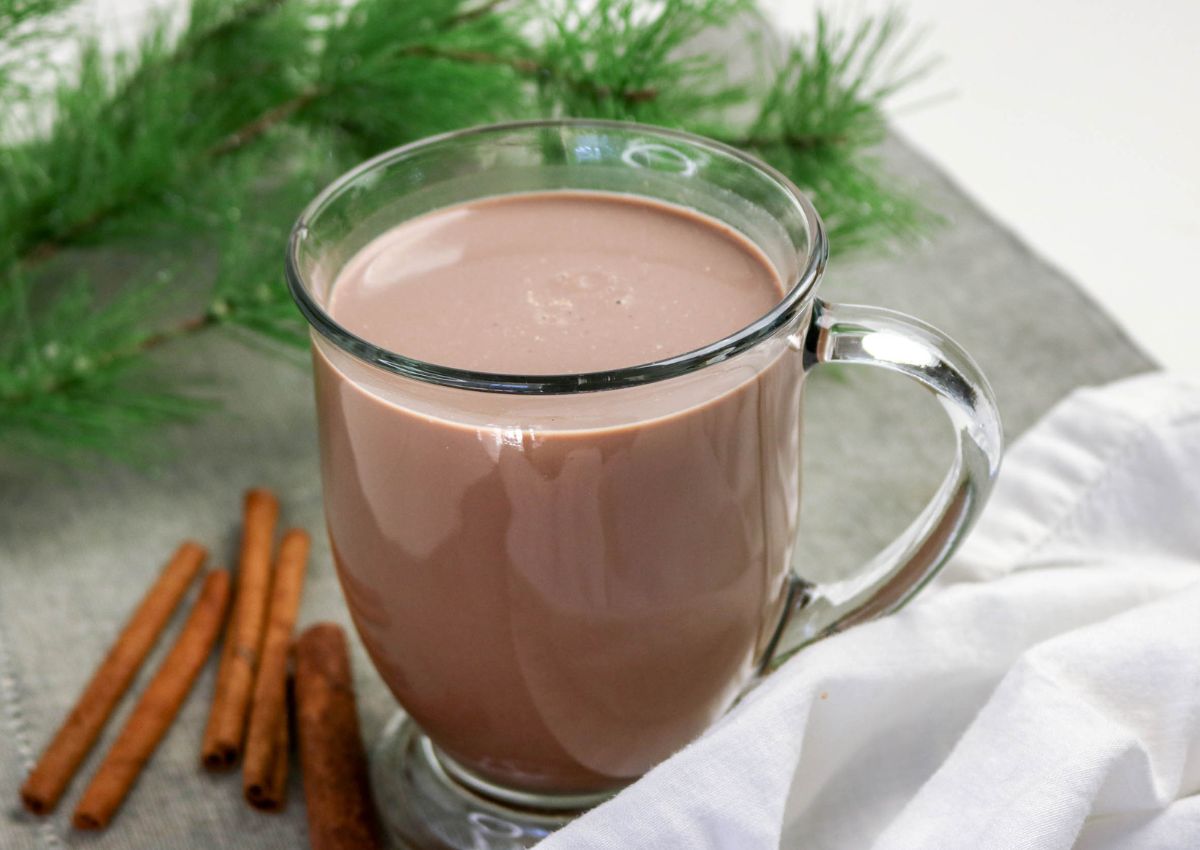 Glass mug of Mexican hot chocolate topped with whipped cream and cinnamon.