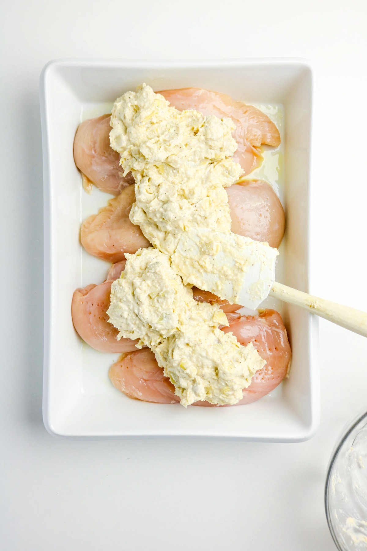 Artichoke mixture over chicken before baking.