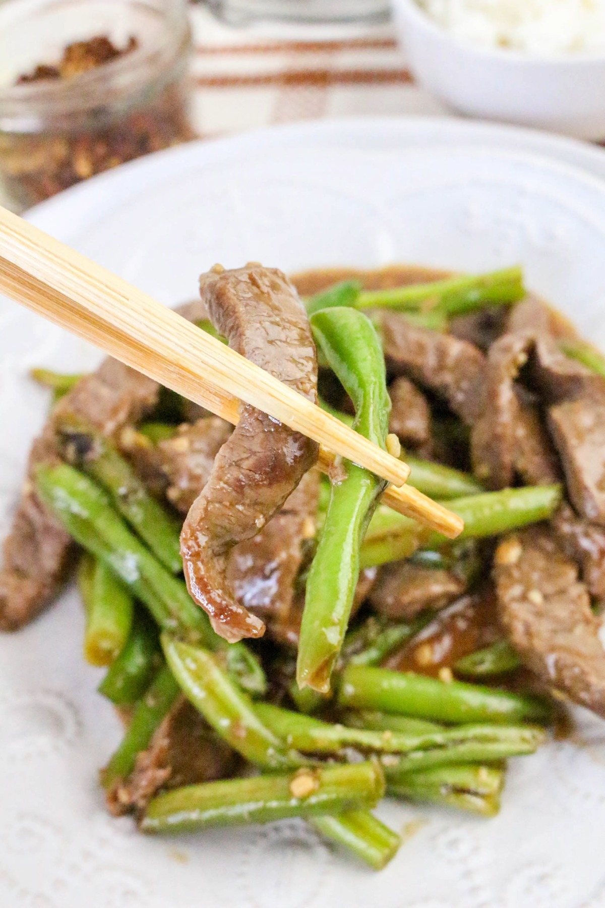 A chopstick with a slice of grren beans and beef.
