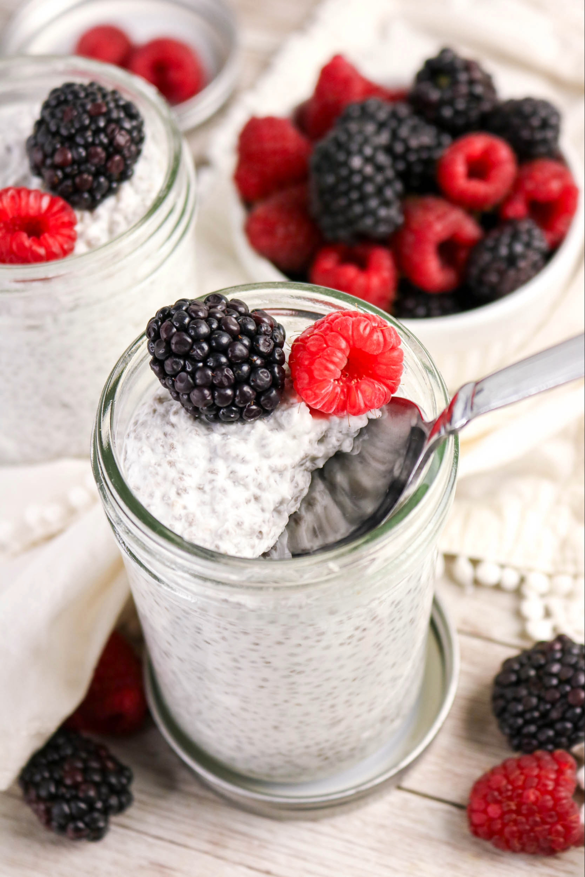 A spoonful of chia pudding in a jar with fresh berries.