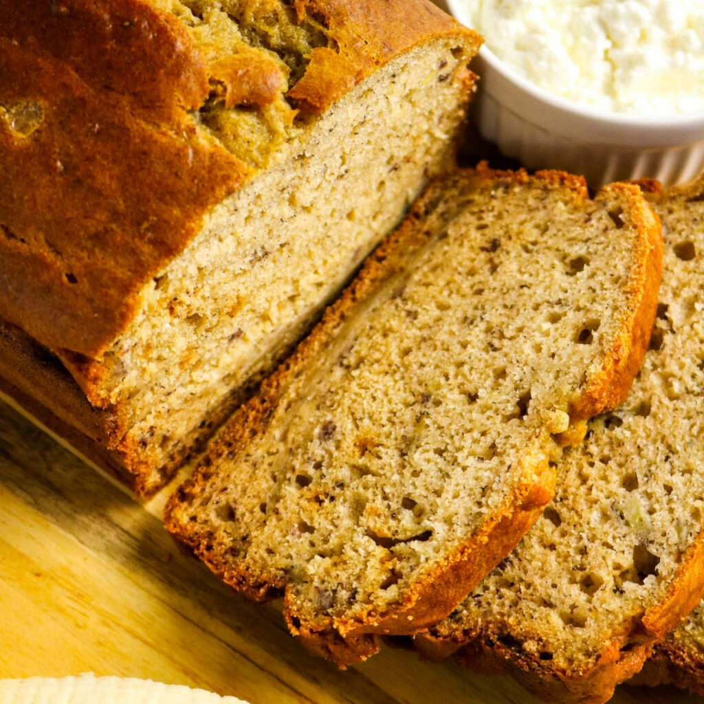 Sliced banana bread on a wood cutting board made with cottage cheese.