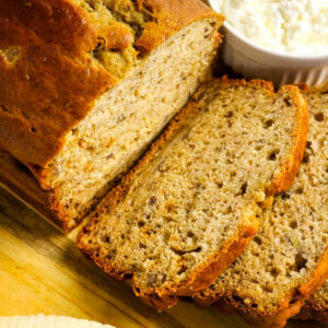Sliced banana bread on a wood cutting board made with cottage cheese.