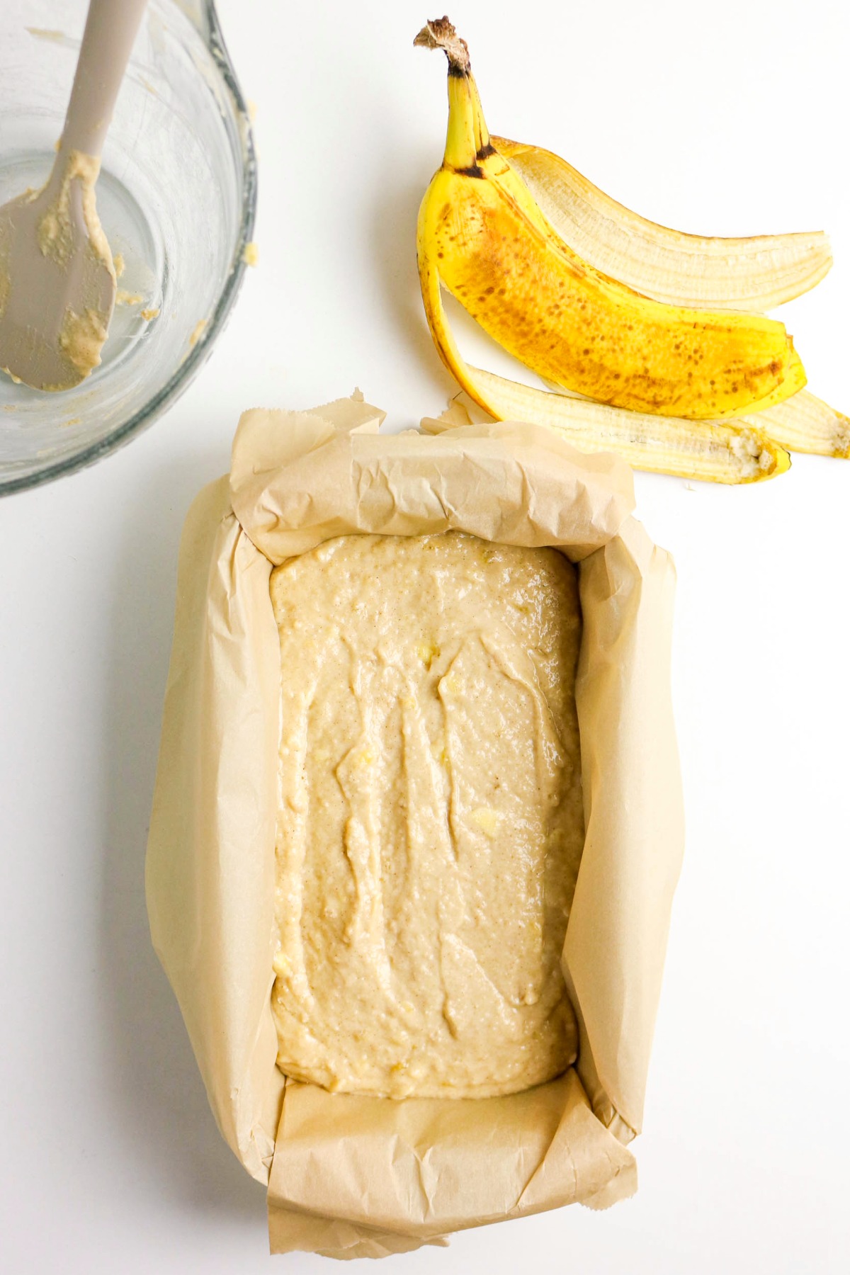 uncooked batter in a parchment lined loaf pan before baking.