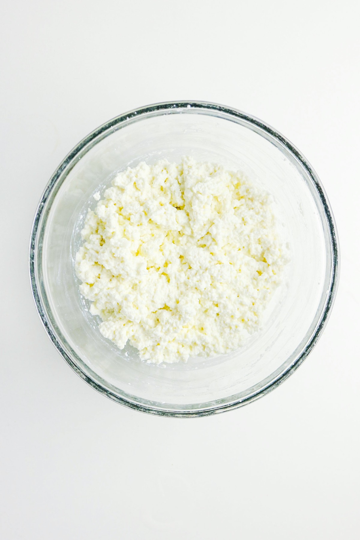Homemade cottage cheese in a clear mixing bowl before refrigerating.
