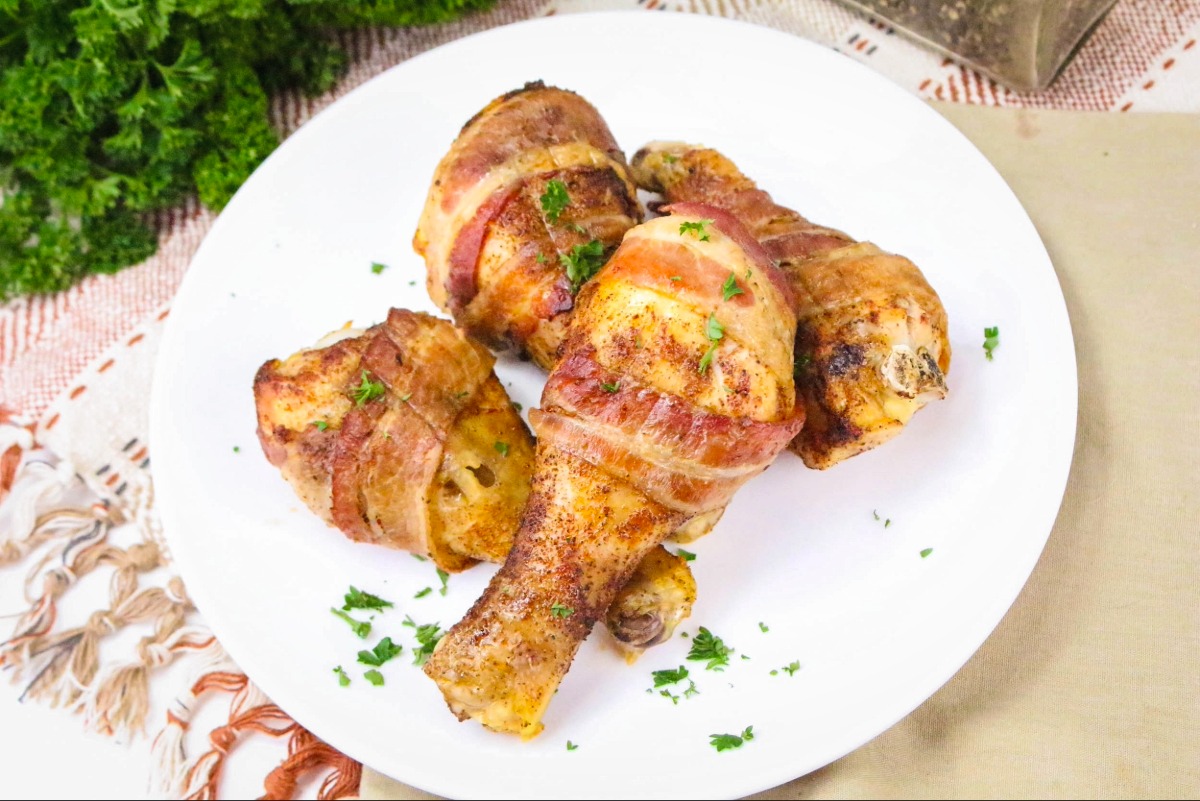 Cooked chicken drumsticks on a white plate.