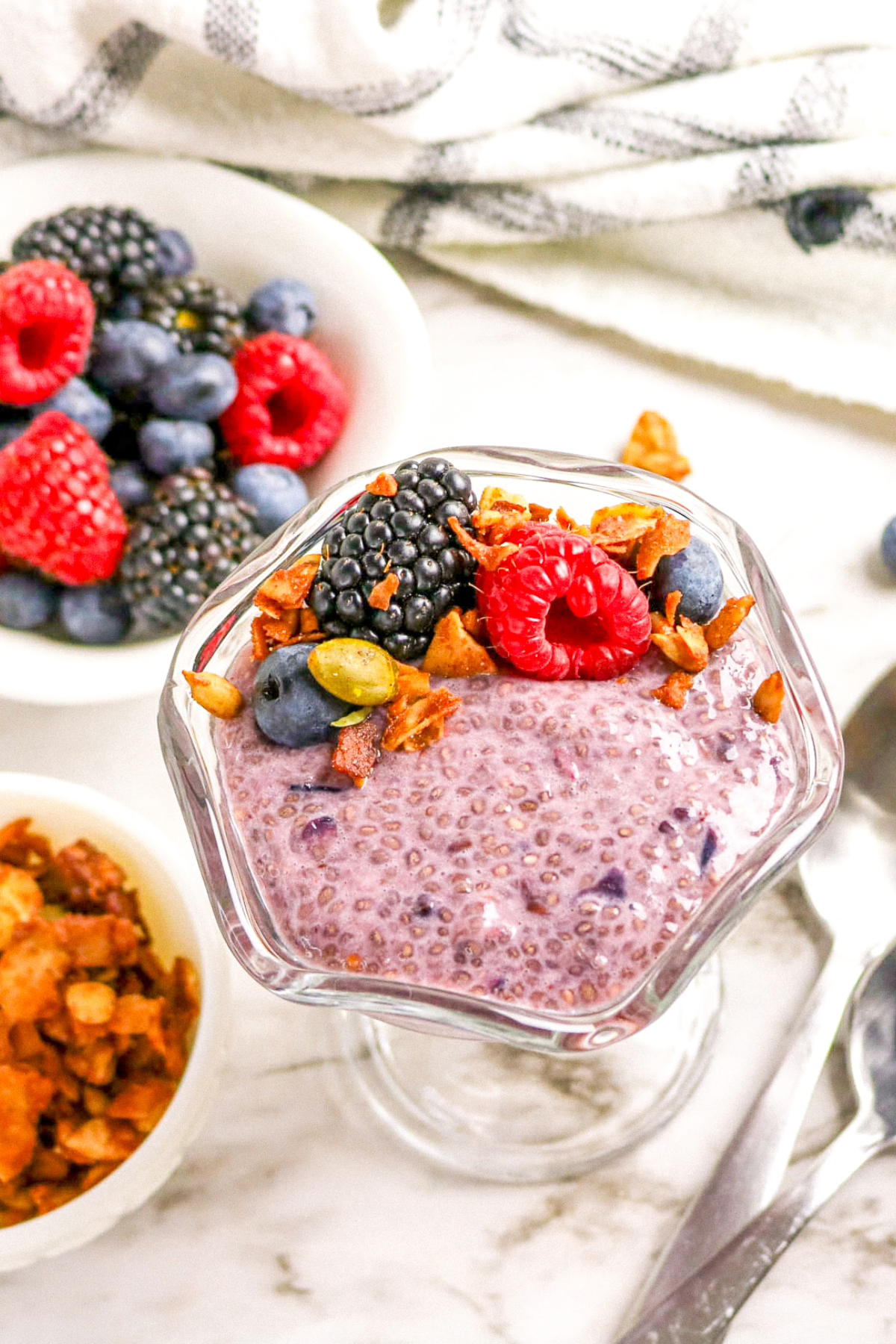 Top view of berry chia pudding topped with fresh berries and granola on the side.