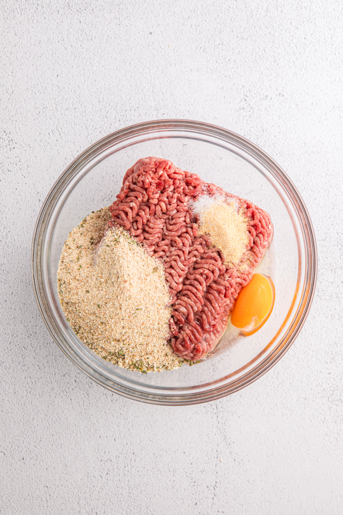 Ingredients in a clear bowl to make meatballs.