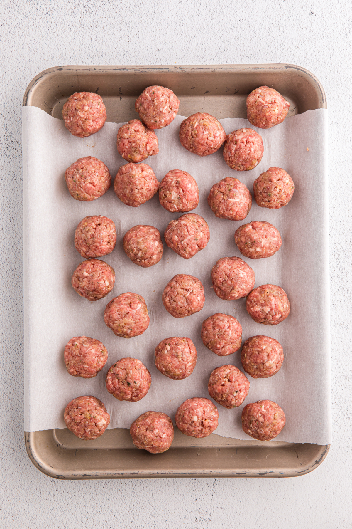 uncooked meatballs on a baking sheet.